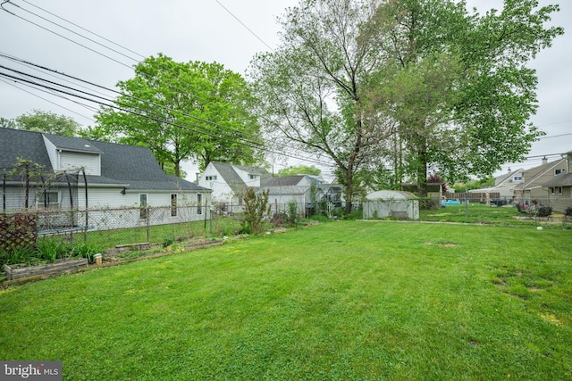 view of yard with a garden, fence, and a residential view