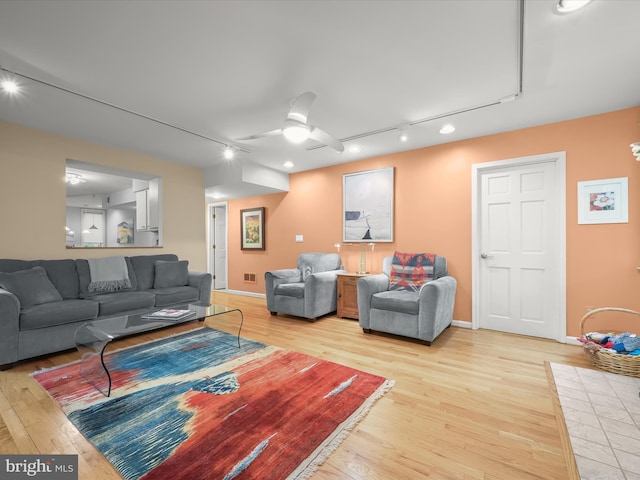 living room featuring track lighting, light wood-style floors, ceiling fan, and baseboards