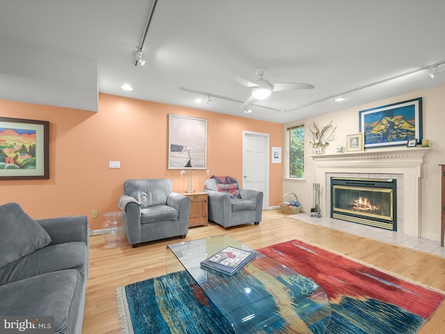 living area with track lighting, a fireplace, wood finished floors, and a ceiling fan
