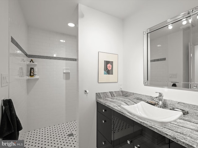 bathroom featuring tiled shower, vanity, and recessed lighting