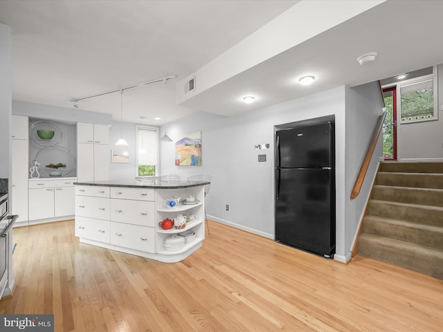 kitchen with freestanding refrigerator, open shelves, rail lighting, light wood-style flooring, and a kitchen island