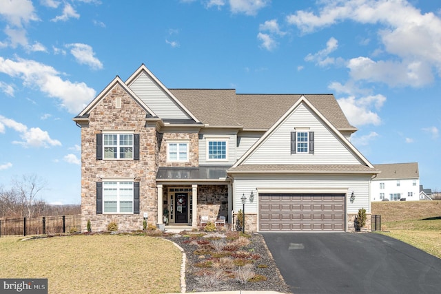 craftsman-style home with fence, a garage, stone siding, aphalt driveway, and a front lawn