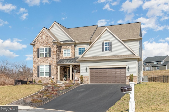 view of front of property with stone siding, driveway, a front lawn, and fence