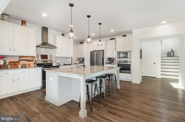 kitchen with recessed lighting, dark wood finished floors, wall chimney exhaust hood, stainless steel appliances, and white cabinets