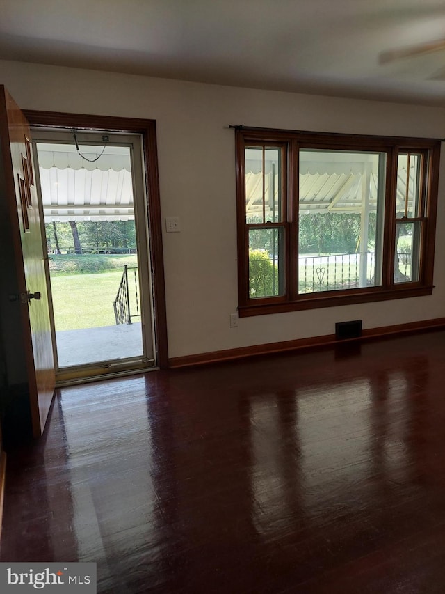 empty room featuring baseboards, wood finished floors, and visible vents