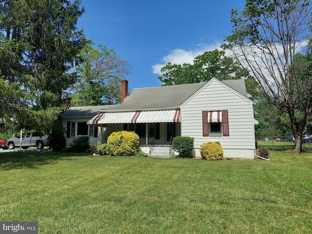 view of front of home featuring a chimney, roof with shingles, and a front yard
