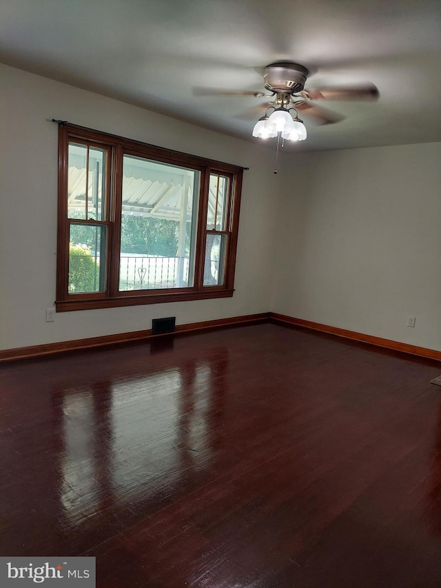 spare room with baseboards, ceiling fan, visible vents, and wood finished floors