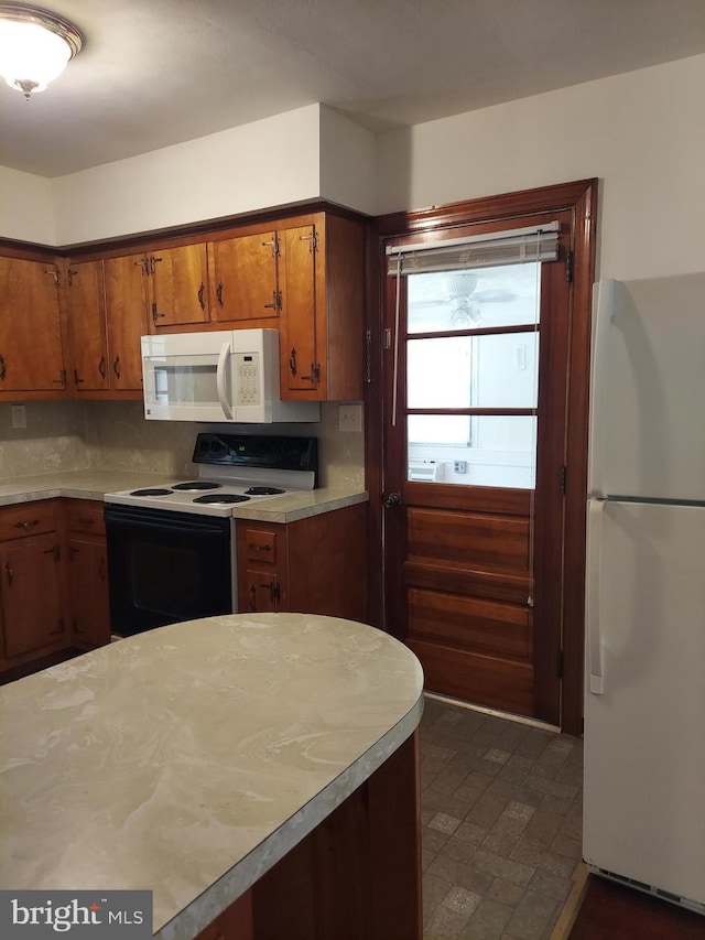 kitchen featuring light countertops, brown cabinets, and white appliances