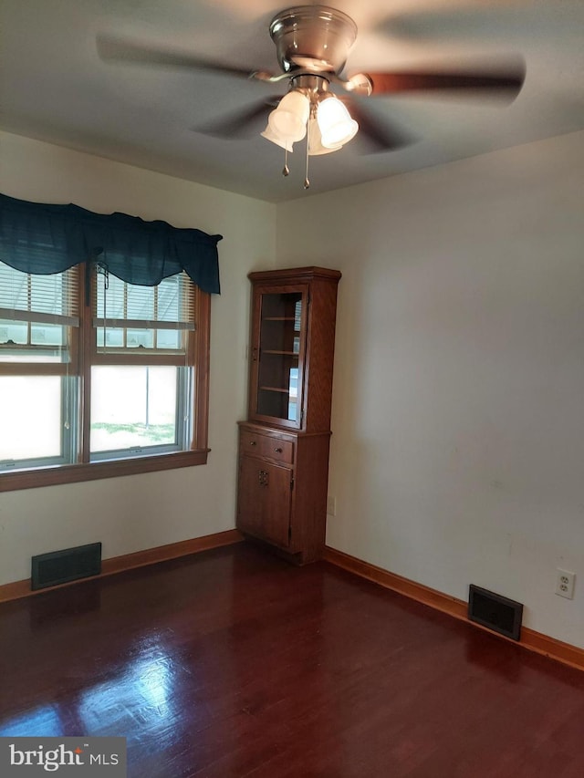 unfurnished room featuring baseboards, ceiling fan, wood finished floors, and visible vents