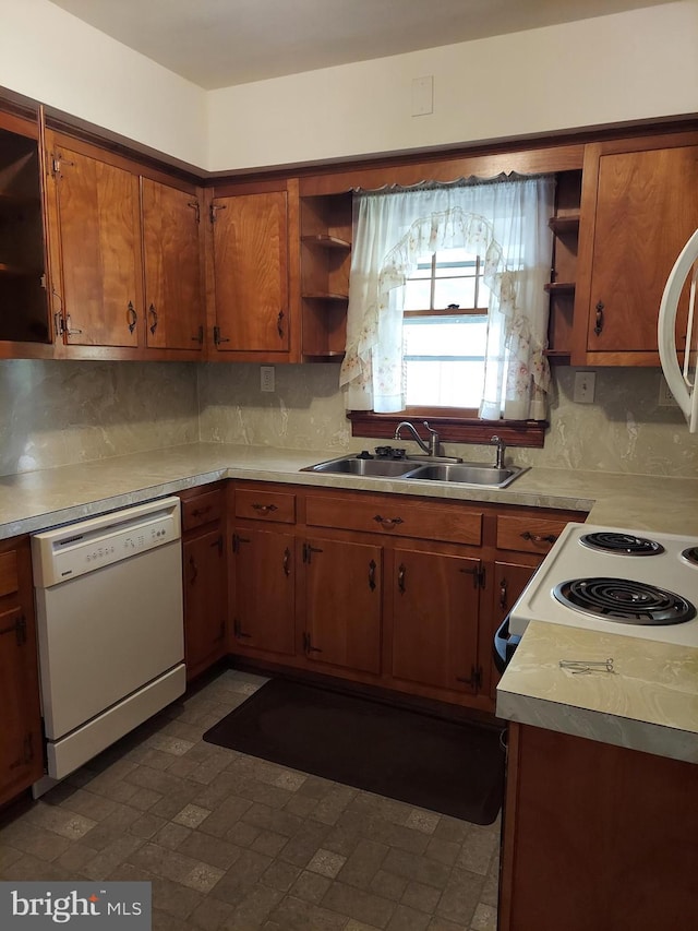 kitchen with white dishwasher, light countertops, open shelves, and a sink