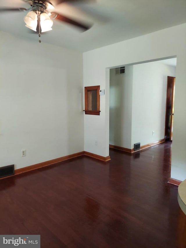 spare room featuring baseboards, ceiling fan, visible vents, and wood finished floors