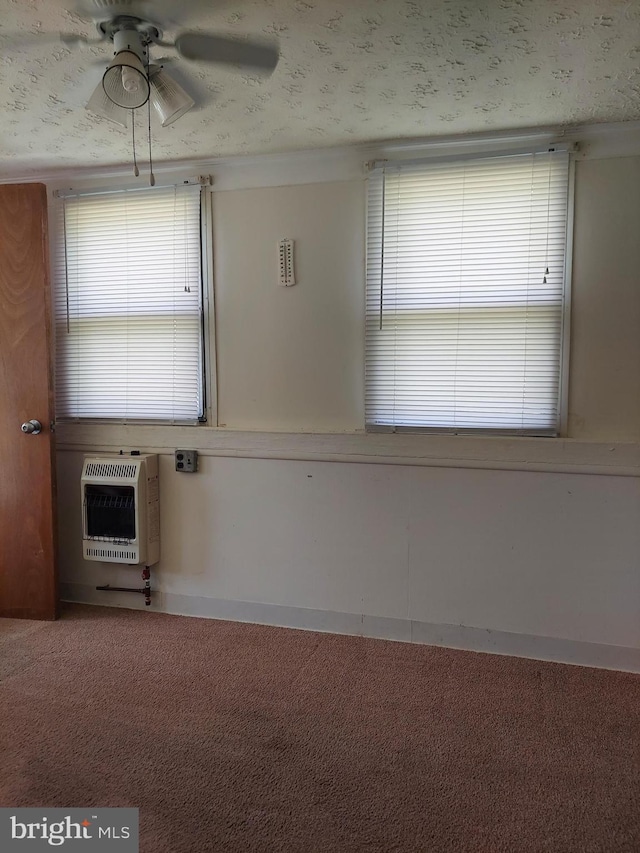 carpeted spare room featuring a ceiling fan and heating unit