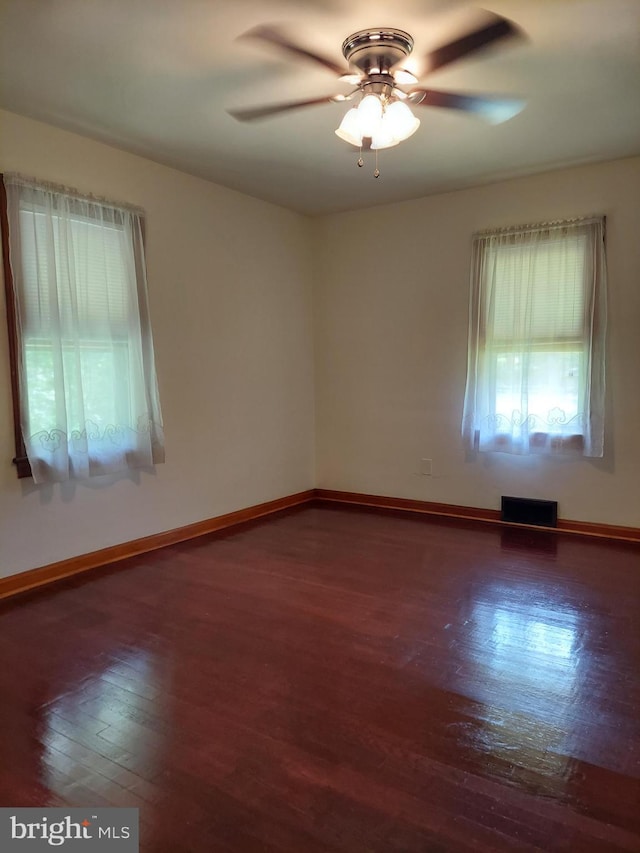 unfurnished room with baseboards, ceiling fan, visible vents, and wood finished floors