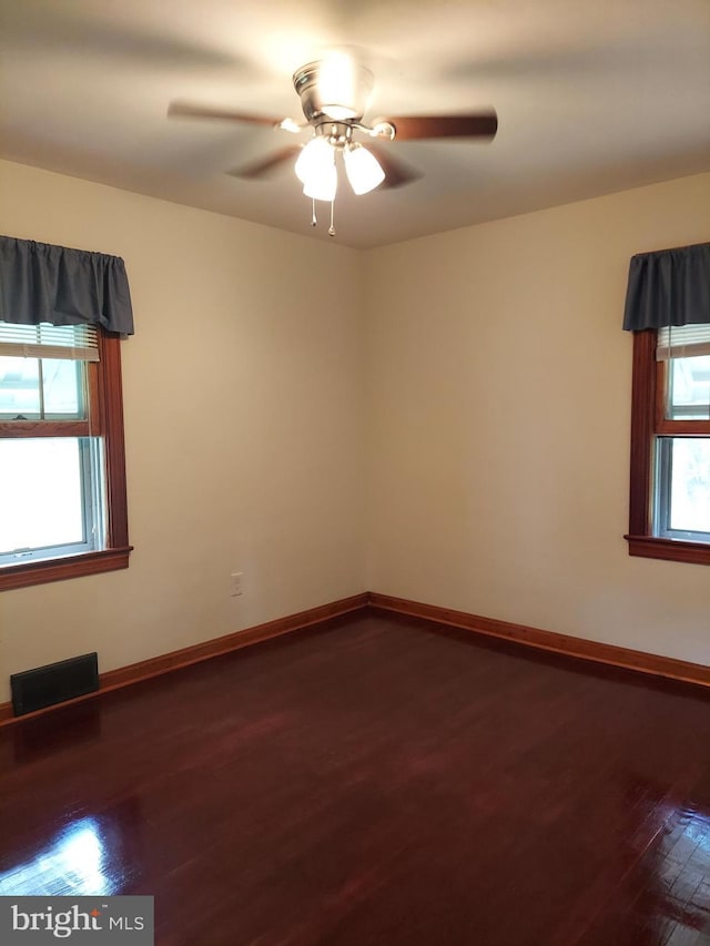 spare room with a healthy amount of sunlight, a ceiling fan, wood finished floors, and visible vents