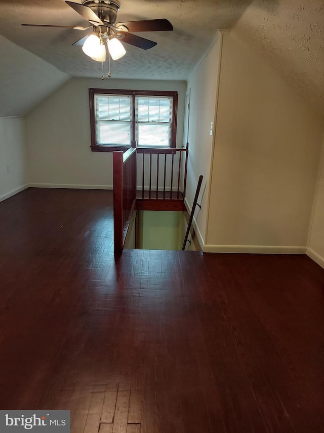 bonus room with a ceiling fan, a textured ceiling, vaulted ceiling, baseboards, and wood-type flooring