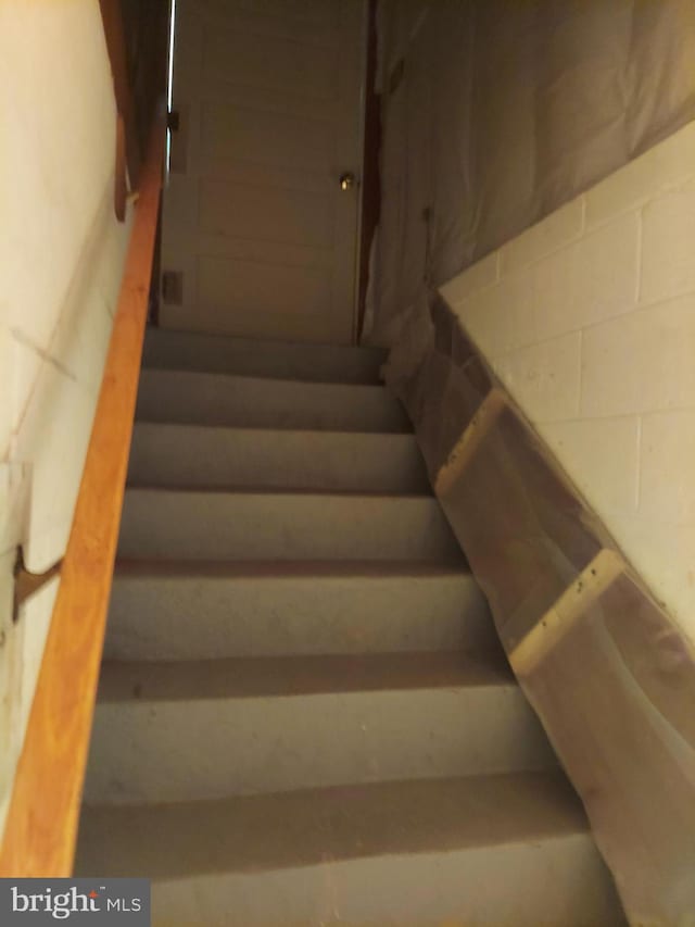 stairway featuring concrete block wall