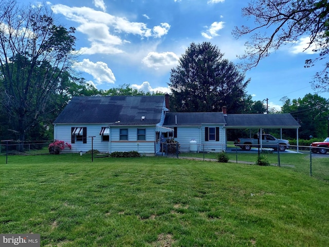 rear view of property with fence, an attached carport, and a lawn