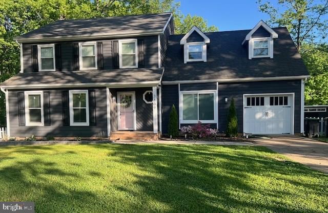 traditional-style home with an attached garage, concrete driveway, and a front yard