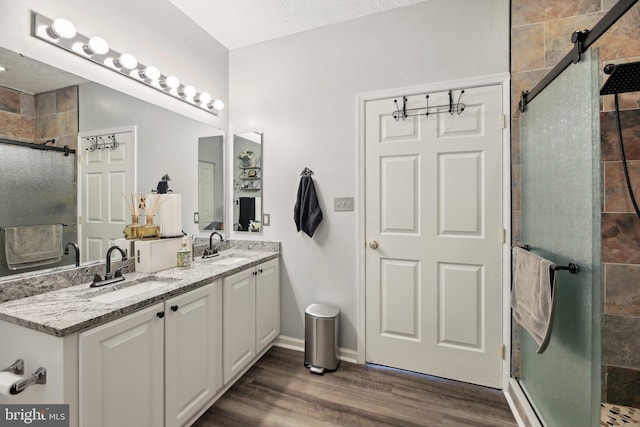 full bathroom with a stall shower, wood finished floors, and double vanity
