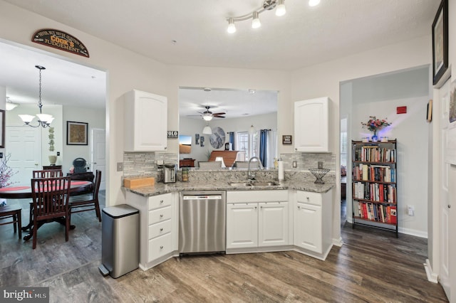 kitchen featuring dishwasher, a sink, backsplash, wood finished floors, and light stone counters
