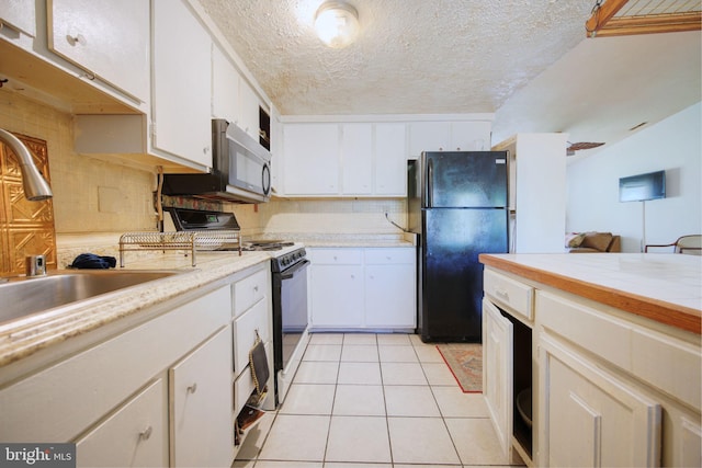 kitchen with a sink, light countertops, freestanding refrigerator, stainless steel microwave, and gas range oven