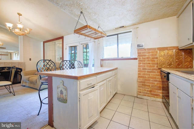 kitchen with a notable chandelier, a breakfast bar area, light countertops, a textured ceiling, and stainless steel dishwasher
