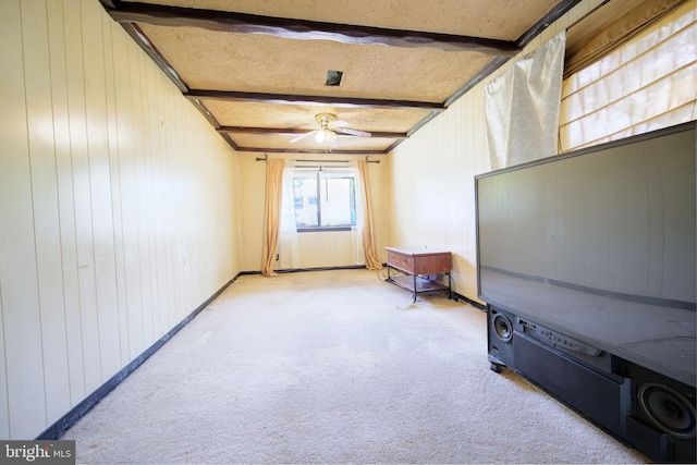 interior space featuring light colored carpet, wood walls, ceiling fan, and beamed ceiling