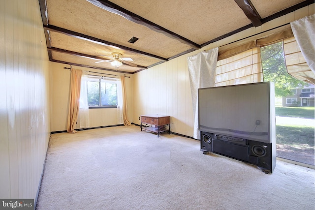 unfurnished room featuring carpet flooring, wood walls, and beamed ceiling