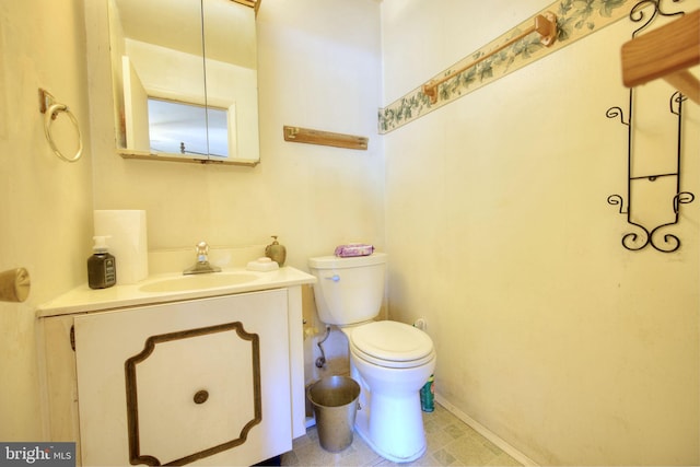 half bath with toilet, baseboards, and vanity
