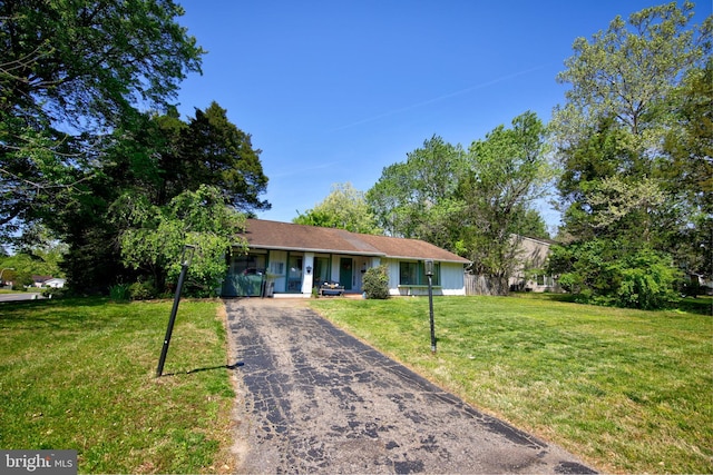 ranch-style house with aphalt driveway, covered porch, and a front yard