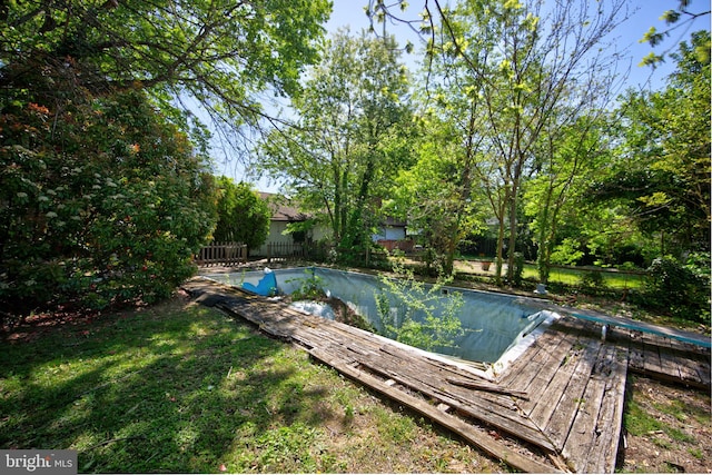 view of swimming pool with a fenced backyard, a covered pool, and a deck