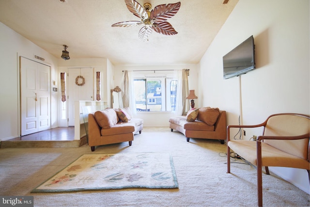 living area with carpet floors, ceiling fan, and a textured ceiling