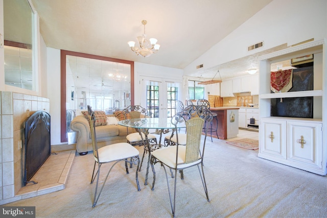 dining room featuring light colored carpet, a notable chandelier, high vaulted ceiling, and visible vents