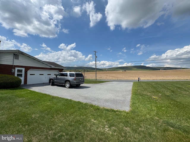 view of yard featuring an attached garage and aphalt driveway