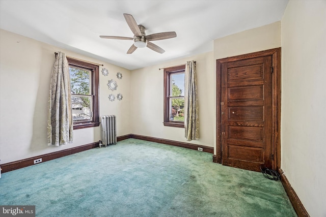 carpeted spare room with radiator, baseboards, and a ceiling fan