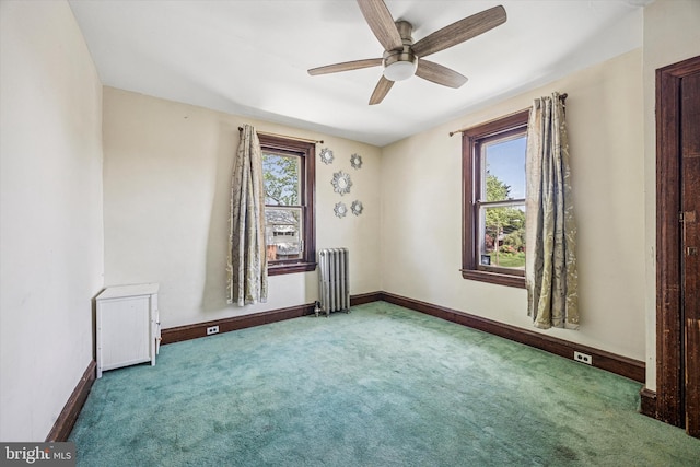 carpeted spare room featuring ceiling fan, baseboards, and radiator