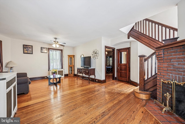 living room with a ceiling fan, stairway, baseboards, and hardwood / wood-style flooring