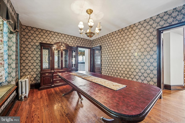 dining area with an inviting chandelier, radiator, wallpapered walls, baseboards, and dark wood-style floors