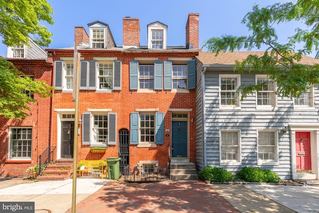 multi unit property featuring brick siding, a chimney, and entry steps