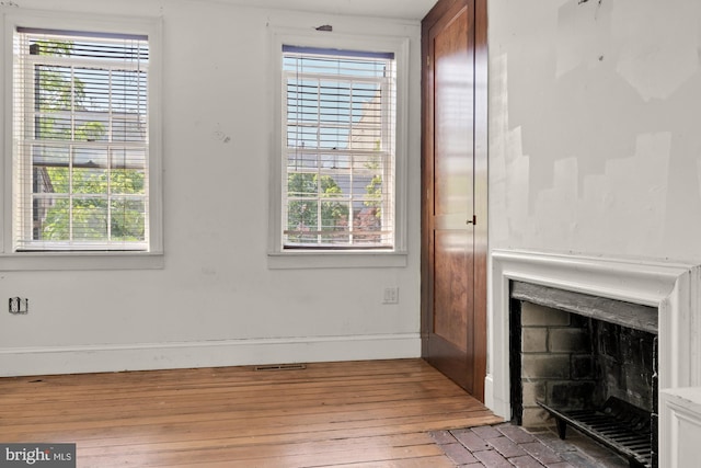 unfurnished living room featuring baseboards, light wood-style flooring, and a fireplace
