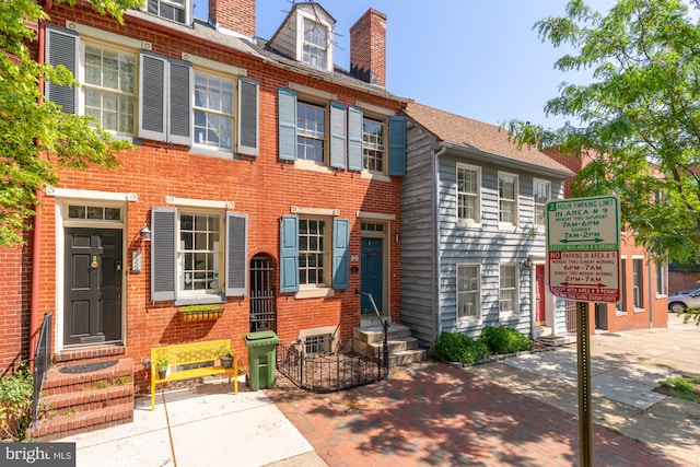 townhome / multi-family property featuring a chimney and brick siding
