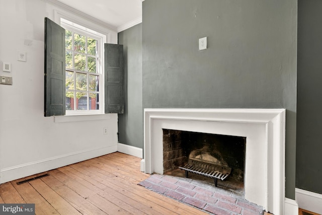 living room with visible vents, crown molding, a fireplace, baseboards, and wood-type flooring