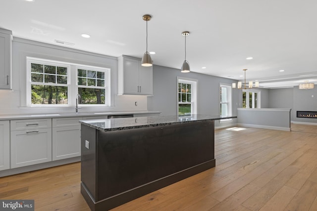 kitchen with backsplash, visible vents, a sink, and a kitchen island
