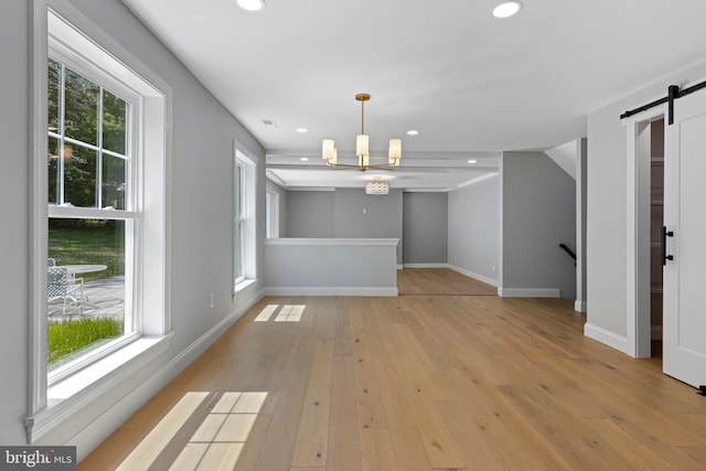unfurnished dining area with an inviting chandelier, a barn door, plenty of natural light, and recessed lighting