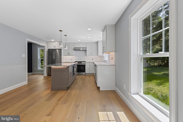kitchen featuring under cabinet range hood, appliances with stainless steel finishes, and plenty of natural light