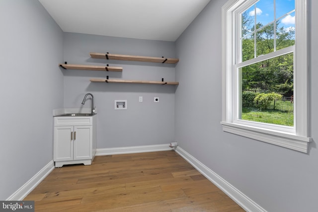 laundry room with a sink, cabinet space, indoor wet bar, hookup for an electric dryer, and light wood-style flooring