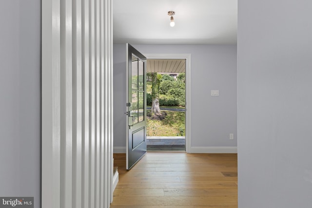 doorway with baseboards and hardwood / wood-style floors