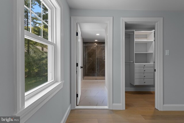 corridor with a wealth of natural light, wood finished floors, and baseboards