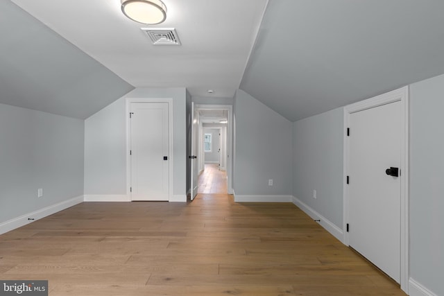 bonus room featuring vaulted ceiling, light wood finished floors, baseboards, and visible vents