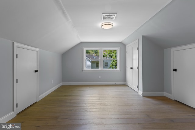 bonus room featuring baseboards, vaulted ceiling, visible vents, and hardwood / wood-style flooring